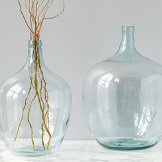 two glass vases sitting on top of a white countertop next to each other