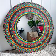 a round mirror sitting on top of a carpeted floor next to a plant in a vase