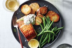 a black plate topped with salmon, green beans and potatoes