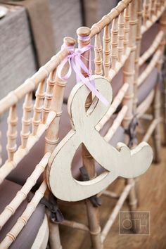 a wooden ampersby sign with a pink ribbon tied to it's back