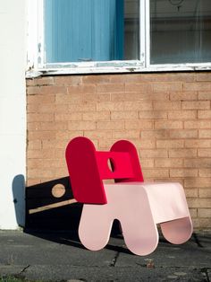 a red and pink chair sitting in front of a brick building