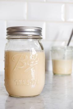 a glass jar filled with liquid sitting on top of a counter next to a cup