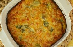 a casserole dish with broccoli and cheese in it on a wicker place mat