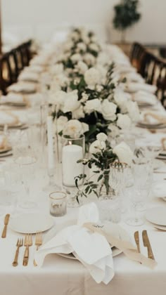 a long table is set with white flowers and place settings