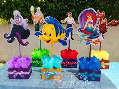 the little mermaid cake toppers are set up on a table in front of some decorations