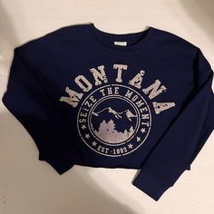 Introducing The Abound Navy Montana Cropped Sweatshirt In Junior Size Small. This Trendy Sweatshirt Features Long Sleeves, A Pullover Closure, And A Collarless Style, Making It Perfect For All Seasons. The Beautiful Blue Color Accentuates Its State Theme And Is Complimented By The Montana Print. Made In China, This Sweatshirt Is Brand New With Tags And Is Perfect For Any Occasion, Especially Activewear. It Is Designed For Juniors And Has A Comfortable Fit. Get Your Hands On This Abound Sweatshir Trendy Navy Top With Letter Print, Navy Oversized Tops With Letter Print, Oversized Navy Tops With Letter Print, Navy Oversized Top With Letter Print, Navy Oversized Graphic Print Top, Blue Casual Sweatshirt With Text Print, Montana Shirt, Knot Sweater, Chevron Sweater