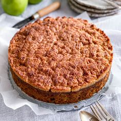 a cake sitting on top of a table next to some silverware and green apples