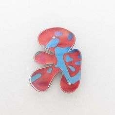 a red and blue brooch sitting on top of a white table