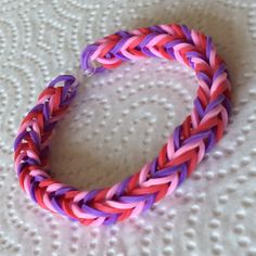 a pink and purple braided bracelet sitting on top of a white surface