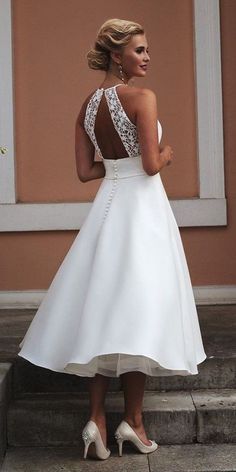 a woman in a white dress is standing on some steps with her back to the camera