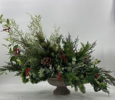 a vase filled with greenery and pine cones