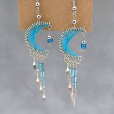 a pair of earrings with blue beads hanging from it's earwires on a cardboard box