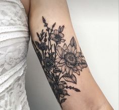 a woman's arm with black and white flowers on the left side of her arm