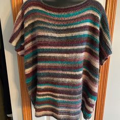 a multicolored sweater hanging on a wooden hanger