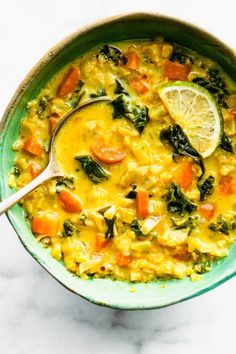 a green bowl filled with soup and topped with a slice of lemon on the side