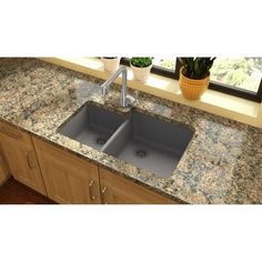 a kitchen sink with granite counter tops and dark wood cabinets, under a window that has potted plants on it