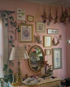 a room with pink walls and lots of pictures on the wall, including a mirror