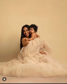 a woman holding a small child in her arms while posing for a photo on the floor