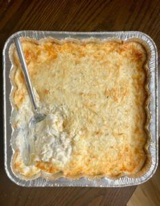 an uncooked casserole dish with a spoon in it on a wooden table