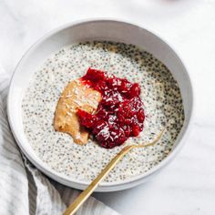 a white bowl filled with oatmeal topped with raspberry jam and sliced almonds