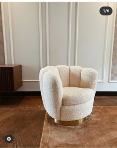 a white chair sitting on top of a wooden floor next to a brown rug and wall