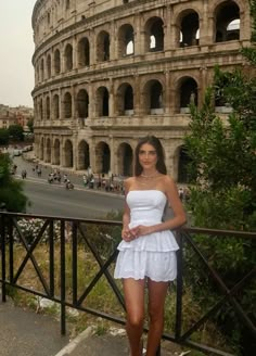 a beautiful young woman standing in front of an old roman collise with her hands on her hips