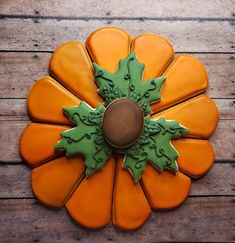 an orange and green flower shaped cookie on a wooden table