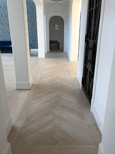 an empty hallway with white walls and wood flooring on either side of the door