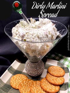 a plate with crackers and cheese on it next to a glass bowl filled with dip