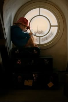 a teddy bear sitting on luggage in front of a round window