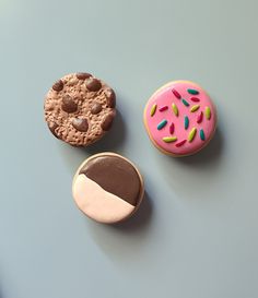 three different types of donuts on a blue surface with chocolate and sprinkles