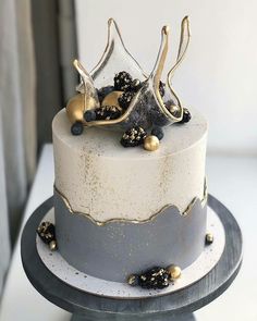 a white and grey cake with gold decorations on it's top, sitting on a table