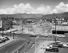 an old black and white photo of cars on the street in front of a town