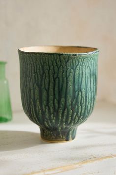 a green vase sitting on top of a white counter