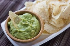 a wooden bowl filled with guacamole and chips