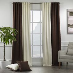 a living room filled with furniture and a large window covered in brown and white curtains