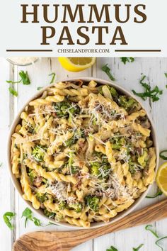 a bowl filled with pasta and broccoli on top of a white wooden table