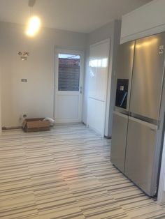 an empty kitchen with stainless steel appliances and tile flooring in the middle of it