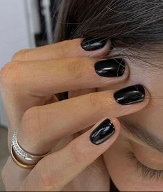 a woman with black nail polish holding her head