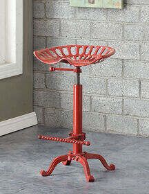 a red stool sitting on top of a cement floor next to a brick wall in front of a window