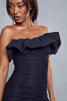 a woman wearing a black dress with ruffles