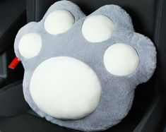 a stuffed animal paw cushion in the back seat of a car, with four white spots on it