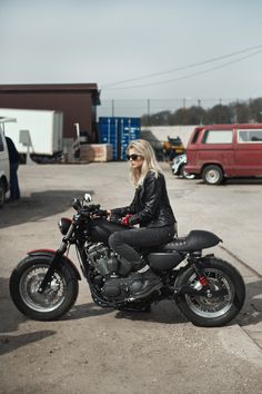 a woman sitting on a motorcycle in a parking lot