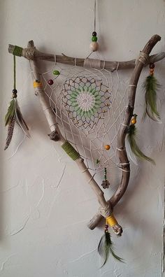 a piece of art made out of branches with beads and feathers hanging from it's sides