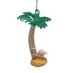 a pink flamingo hanging from a palm tree