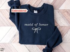 an embroidered sweatshirt with the words maid of honor written in white ink on it