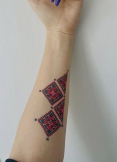 a woman's arm with a red and black tattoo on it, which is decorated with geometric designs