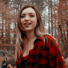 a woman in a red and black checkered shirt smiles at the camera while people stand around her