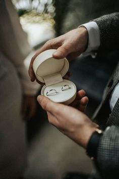 a man holding an open ring box in his hand