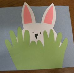 an easter bunny made out of paper on top of a blue and green piece of paper